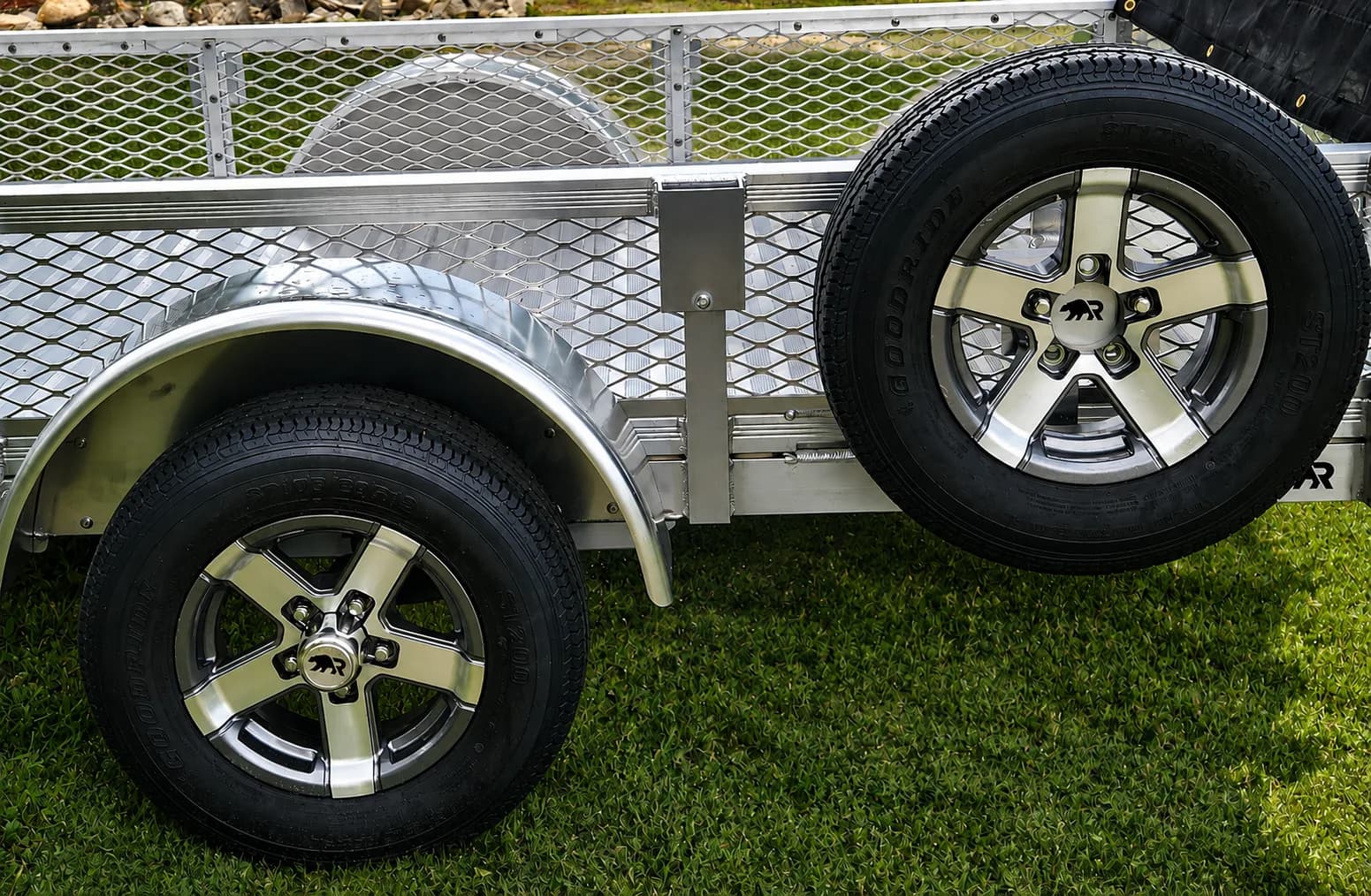 A 13-inch five-star aluminum wheel on a 5-foot Rugged utility trailer, with a matching spare on the mesh side rail