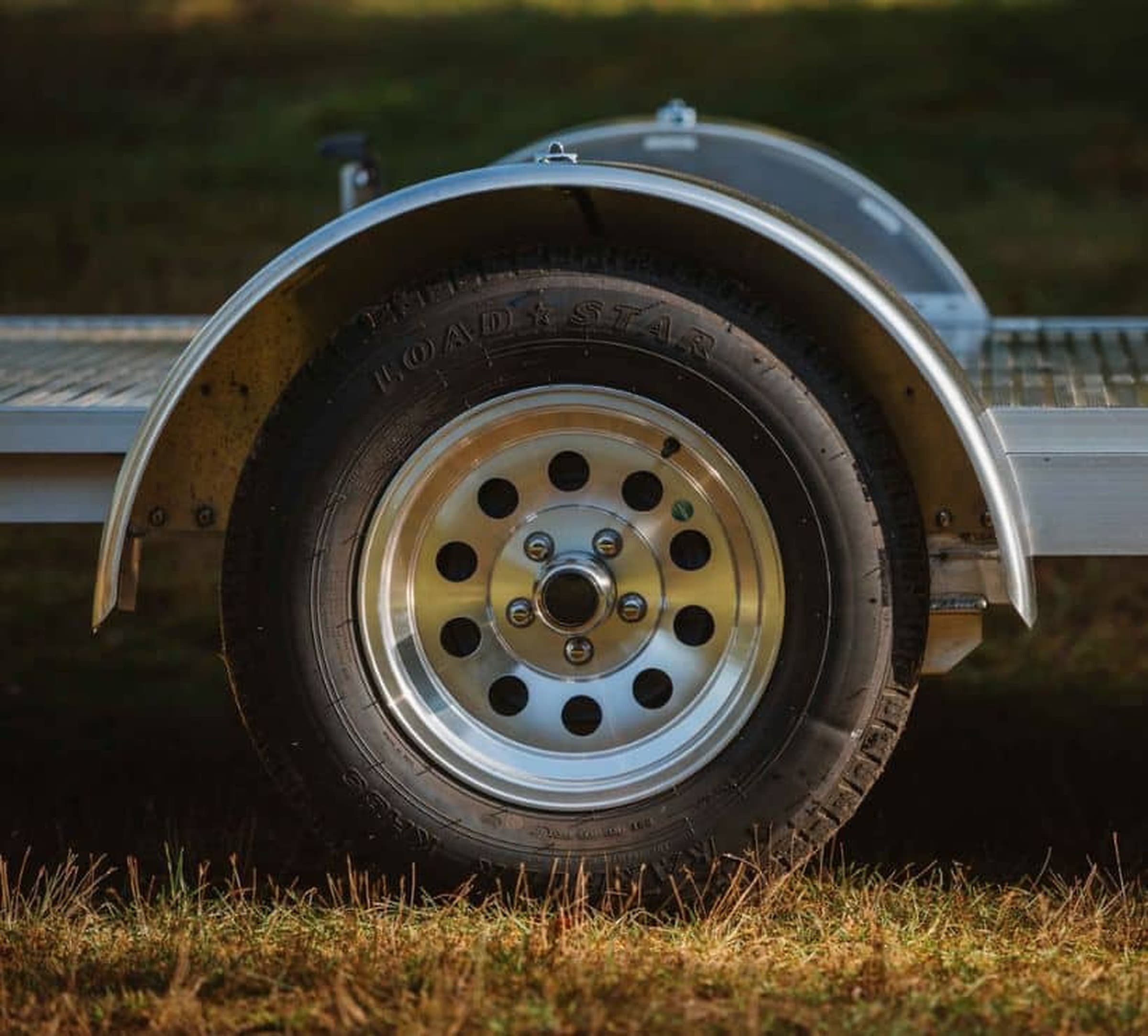 Close-up of a Rugged aluminum mod wheel and aluminum fender on a finished trailer outdoors.