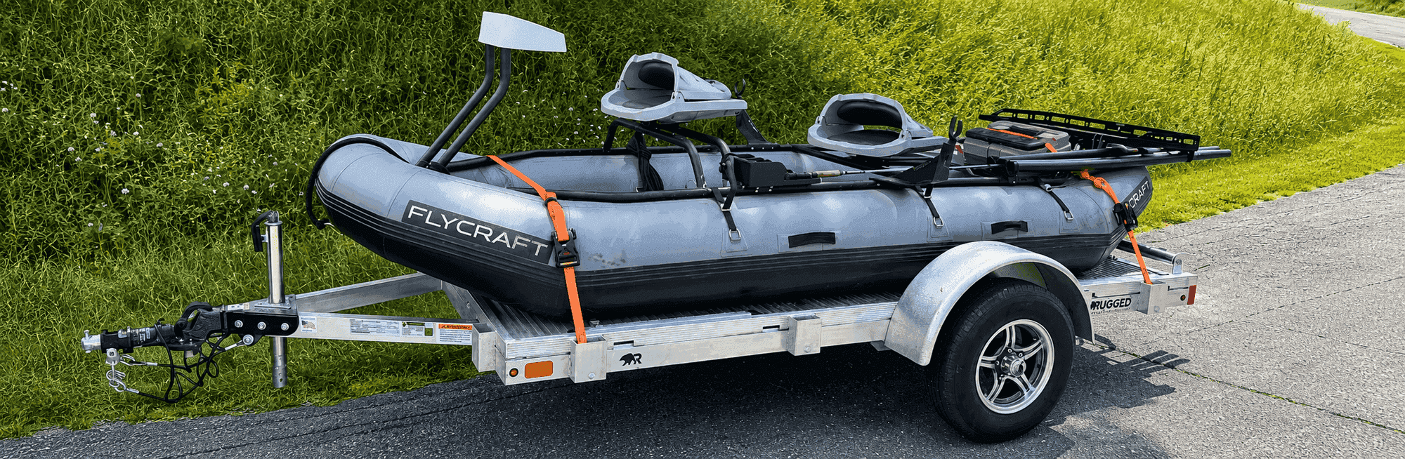 Rugged 5 × 8 utility trailer carrying a Flycraft inflatable fishing boat, strapped and roadside