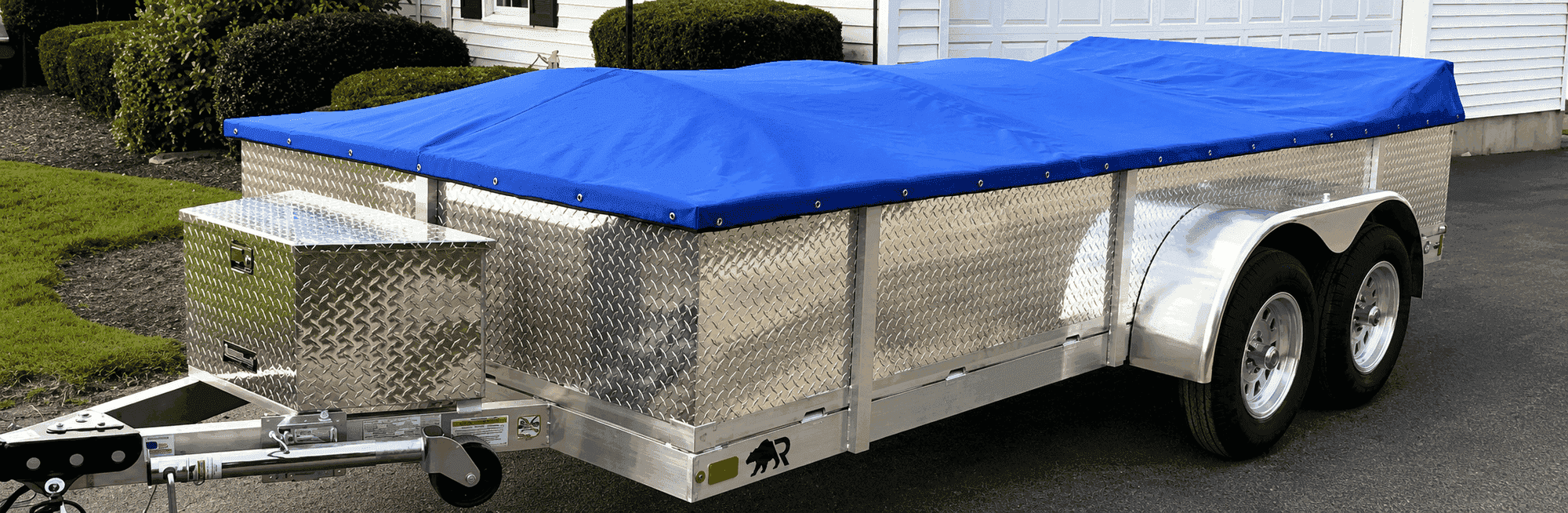 Rugged 6.5 × 16 tandem-axle utility trailer with diamond-plate side kit, tongue box, and fitted tarp in a customer driveway