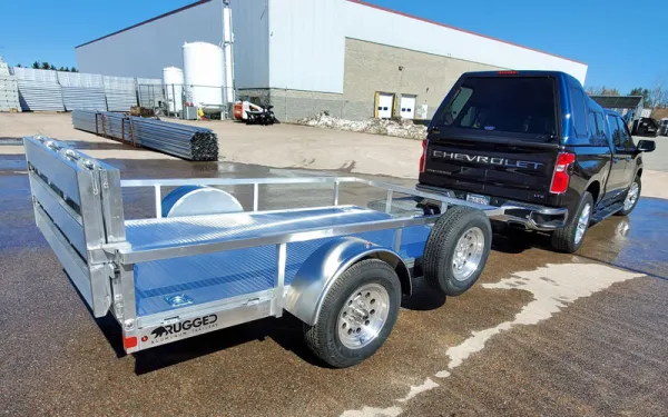 a black Chevy truck parked with a silver trailer attached to the back