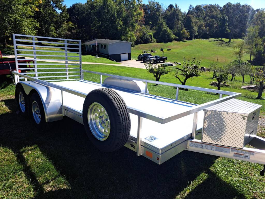 silver trailer with side rails parked in the grass