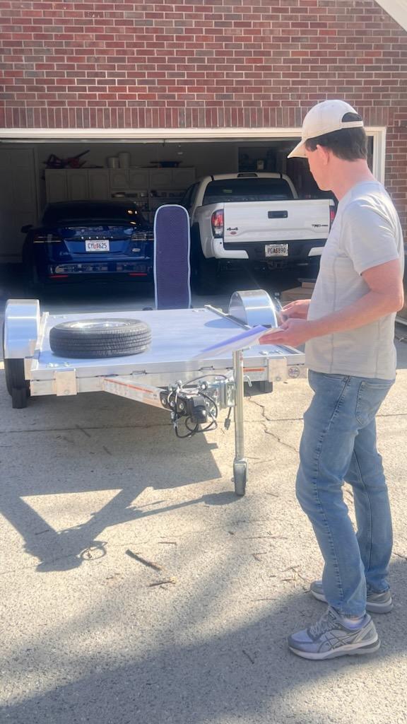 Tim B standing next to a trailer with a tire on it in a driveway