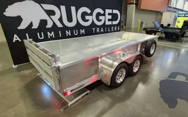 silver trailer parked in front of a Rugged Aluminum Trailers sign