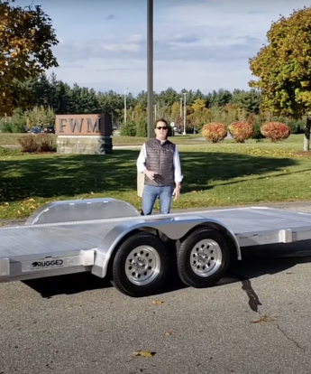 6.5' x 15' Dual Axle Utility Trailer Stow Away Ramp parked outside with a man in the background