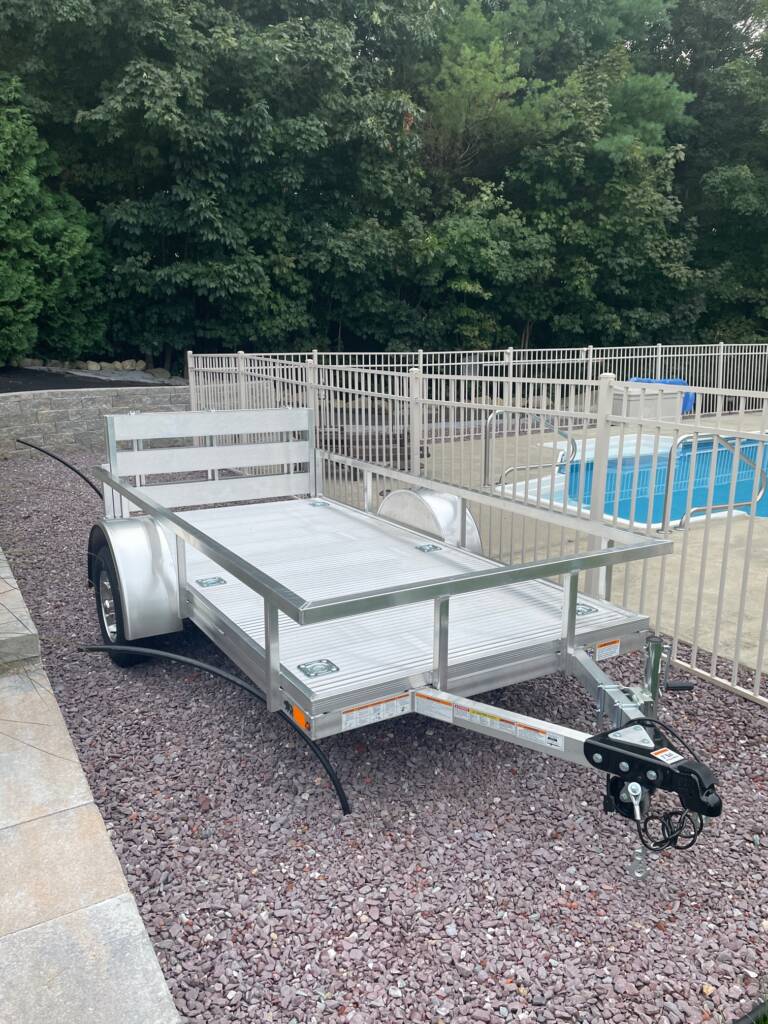 silver trailer with side rails parked by a gated pool