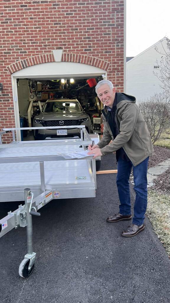 Brian L standing next to trailer with side rails in a driveway