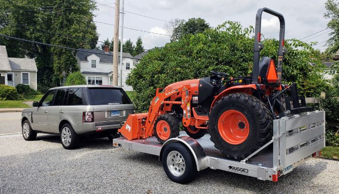 Range Rover towing a trailer with farm equipment on it